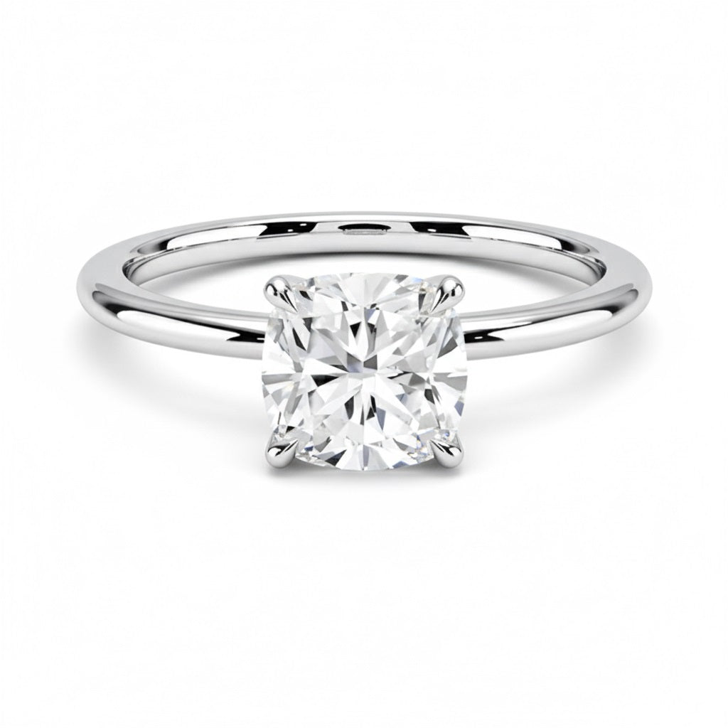 Cushion cut Moissanite lab grown diamond engagement ring round shank with a four claw setting, on a gold band, against a white background.Moissanite engagement ring cape town south africa grand diamonds ralph jacobs jeulia