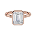 alt="An Emarald cut Moissanite engagement ring round shank with a bezel setting, on a gold band, against a white background.Moissanite engagement ring cape town south africa grand diamonds ralph jacobs jeulia