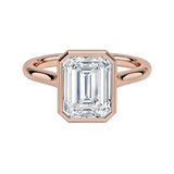 alt="An Emarald cut Moissanite engagement ring round shank with a bezel setting, on a gold band, against a white background.Moissanite engagement ring cape town south africa grand diamonds ralph jacobs jeulia