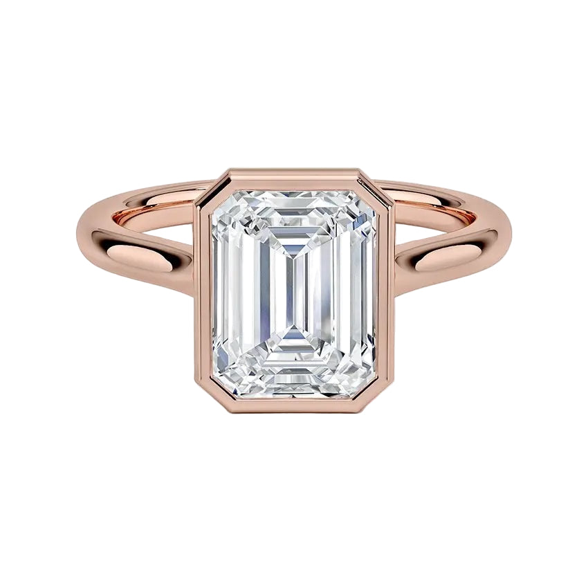 alt="An Emarald cut Moissanite engagement ring round shank with a bezel setting, on a gold band, against a white background.Moissanite engagement ring cape town south africa grand diamonds ralph jacobs jeulia