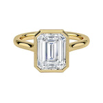 alt="An Emarald cut Moissanite engagement ring round shank with a bezel setting, on a gold band, against a white background.Moissanite engagement ring cape town south africa grand diamonds ralph jacobs jeulia "