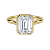 alt="An Emarald cut Moissanite engagement ring round shank with a bezel setting, on a gold band, against a white background.Moissanite engagement ring cape town south africa grand diamonds ralph jacobs jeulia "