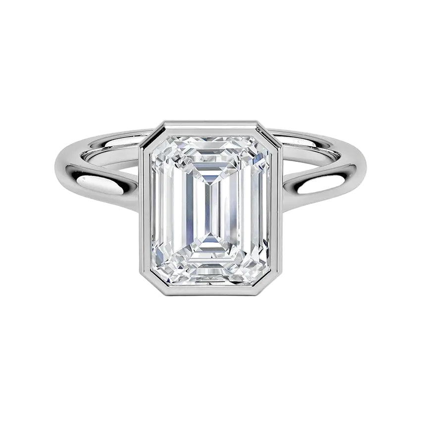 alt="An Emarald cut Moissanite engagement ring round shank with a bezel setting, on a gold band, against a white background.Moissanite engagement ring cape town south africa grand diamonds ralph jacobs jeulia