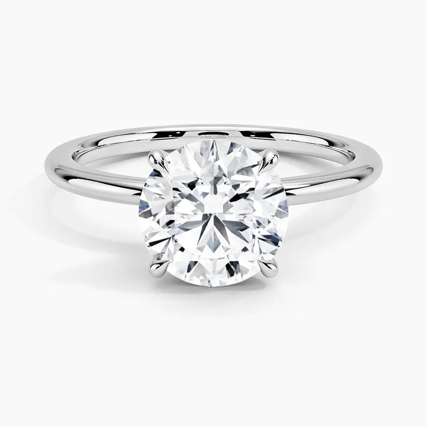 Engagement ring round cut Moissanite lab grown diamond engagement ring round shank with a four claw setting, on a gold band, against a white background.Moissanite engagement ring cape town south africa grand diamonds ralph jacobs jeulia