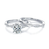 alt="A set of elegant oval engagement and wedding rings with a twisted design, displayed in white gold with diamond accents"