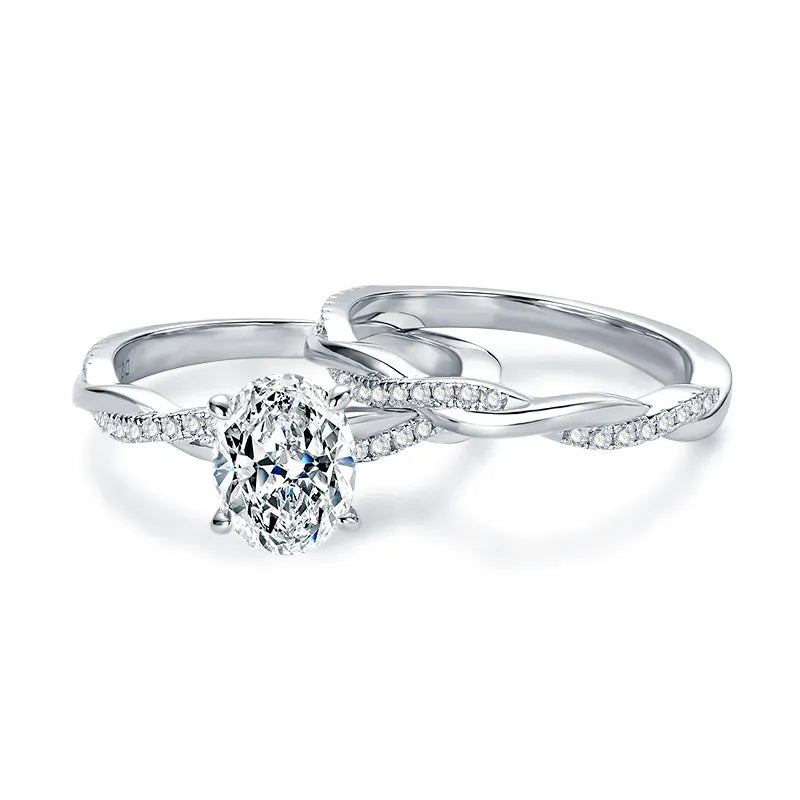 alt="A set of elegant oval engagement and wedding rings with a twisted design, displayed in white gold with diamond accents"