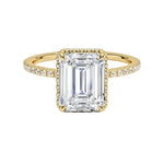 alt="Gold ring with a large Emerald diamond and smaller diamonds on the band against a white background"