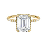 alt="Gold ring with a large Emerald diamond and smaller diamonds on the band against a white background"