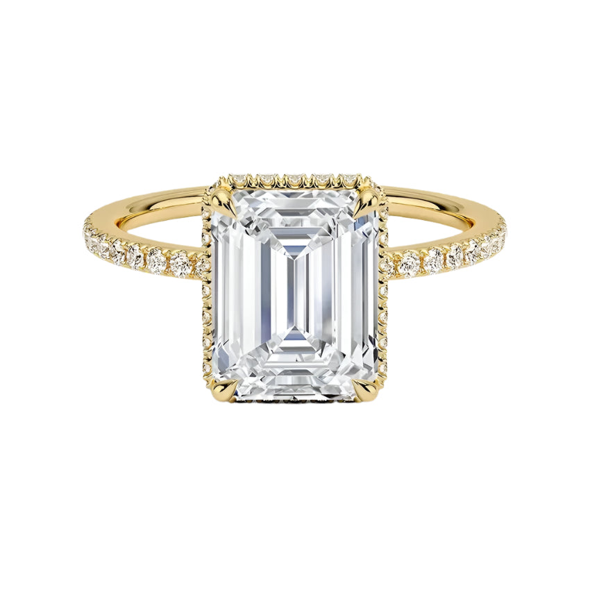 alt="Gold ring with a large Emerald diamond and smaller diamonds on the band against a white background"
