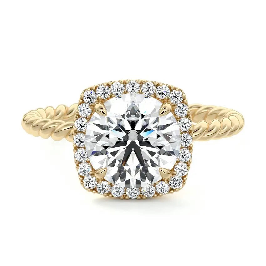alt="A round-cut halo twist band moissanite engagement ring with a yellow gold band and a clear central stone surrounded by smaller clear stones"
