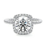 alt="Round-cut moissanite engagement ring with a halo and a twisted pavé band by ApolloGem"