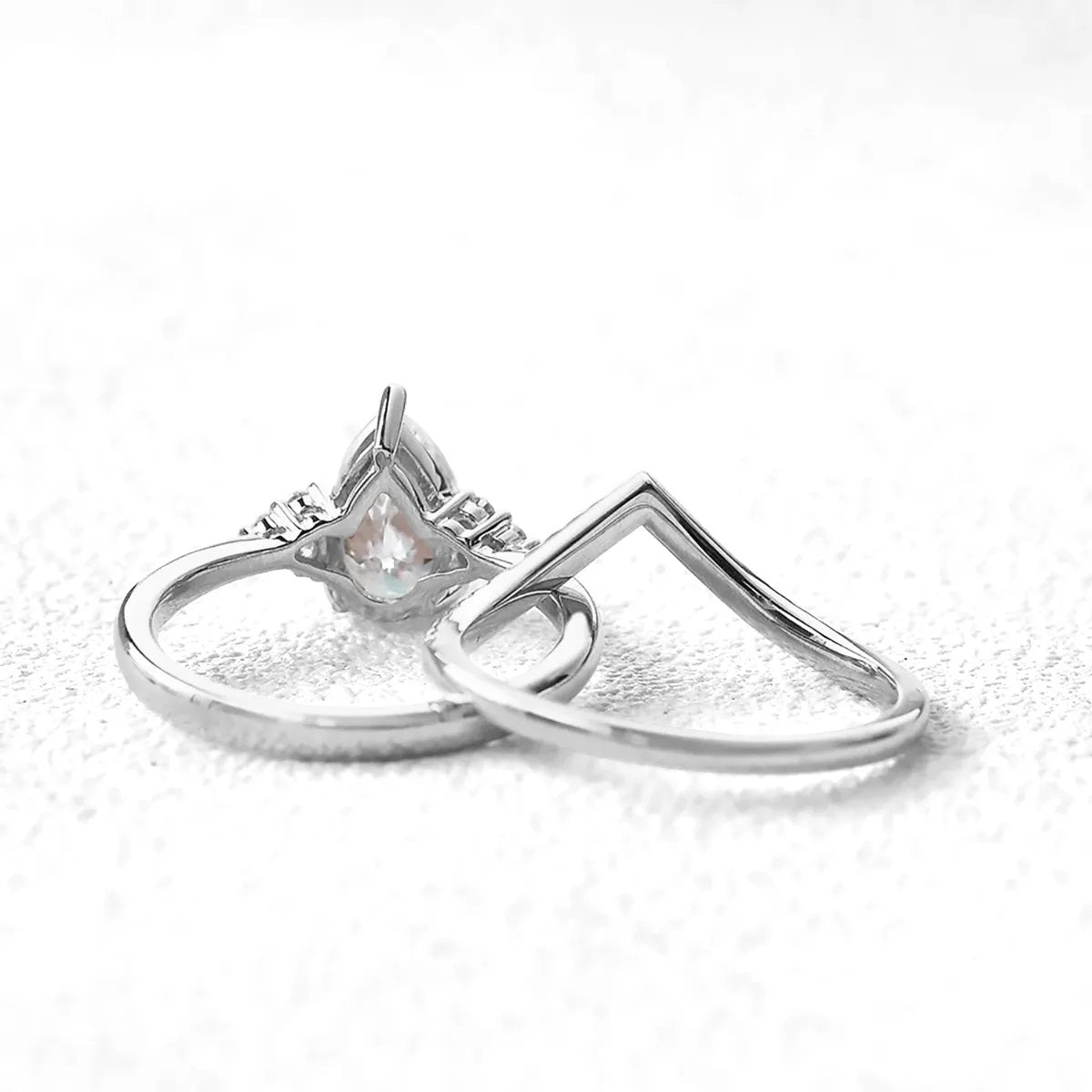 alt="Pear cut moissanite engagement ring cape town set with a matching half eternity V-shaped wedding band by ApolloGem"