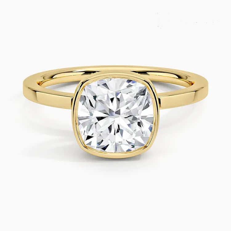 alt="An Cushion cut Moissanite engagement ring with a bezel setting, displayed on a gold band, against a white background.Moissanite engagement ring cape town south africa grand diamonds ralph jacobs jeulia "