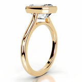 alt="An Emarald cut Moissanite engagement ring round shank with a bezel setting, on a gold band, against a white background.Moissanite engagement ring cape town south africa grand diamonds ralph jacobs jeulia lab grown diamond"