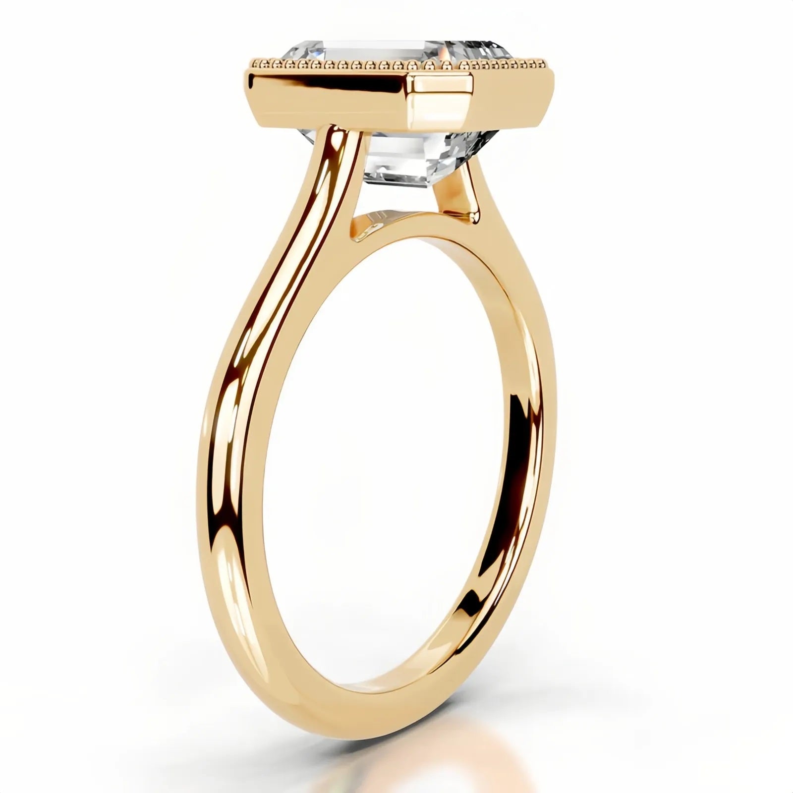 alt="An Emarald cut Moissanite engagement ring round shank with a bezel setting, on a gold band, against a white background.Moissanite engagement ring cape town south africa grand diamonds ralph jacobs jeulia lab grown diamond"