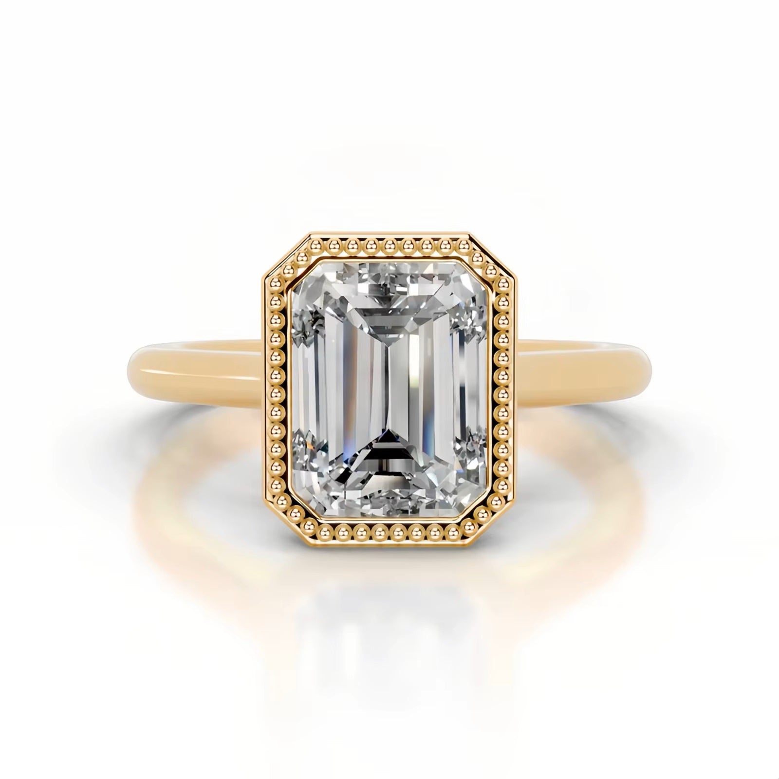 alt="An Emarald cut Moissanite engagement ring round shank with a bezel setting, on a gold band, against a white background.Moissanite engagement ring cape town south africa grand diamonds ralph jacobs jeulia 