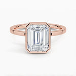 alt="An Emarald cut Moissanite engagement ring with a bezel setting, displayed on a gold band, against a white background.Moissanite engagement ring cape town south africa grand diamonds ralph jacobs jeulia "