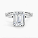 alt="An Emarald cut Moissanite engagement ring with a bezel setting, displayed on a gold band, against a white background.Moissanite engagement ring cape town south africa grand diamonds ralph jacobs jeulia "