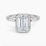 alt="An Emarald cut Moissanite engagement ring with a bezel setting, displayed on a gold band, against a white background.Moissanite engagement ring cape town south africa grand diamonds ralph jacobs jeulia "