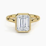 alt="An Emarald cut Moissanite engagement ring round shank with a bezel setting, on a gold band, against a white background.Moissanite engagement ring cape town south africa grand diamonds ralph jacobs jeulia "