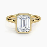alt="An Emarald cut Moissanite engagement ring round shank with a bezel setting, on a gold band, against a white background.Moissanite engagement ring cape town south africa grand diamonds ralph jacobs jeulia "
