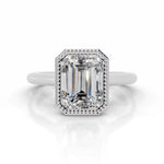 alt="An Emarald cut Moissanite engagement ring round shank with a bezel setting, on a gold band, against a white background.Moissanite engagement ring cape town south africa grand diamonds ralph jacobs jeulia 