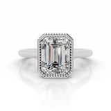 alt="An Emarald cut Moissanite engagement ring round shank with a bezel setting, on a gold band, against a white background.Moissanite engagement ring cape town south africa grand diamonds ralph jacobs jeulia 