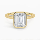 alt="An Emarald cut Moissanite engagement ring with a bezel setting, displayed on a gold band, against a white background.Moissanite engagement ring cape town south africa grand diamonds ralph jacobs jeulia "