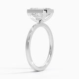 alt="An Emarald cut Moissanite engagement ring with a bezel setting, displayed on a gold band, against a white background.Moissanite engagement ring cape town south africa grand diamonds ralph jacobs jeulia "
