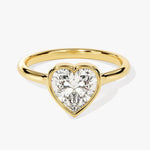  Heart shae Moissanite lab grown diamond engagement ring round shank with a bezel setting, on a gold band, against a white background.Moissanite engagement ring cape town south africa grand diamonds ralph jacobs jeulia 