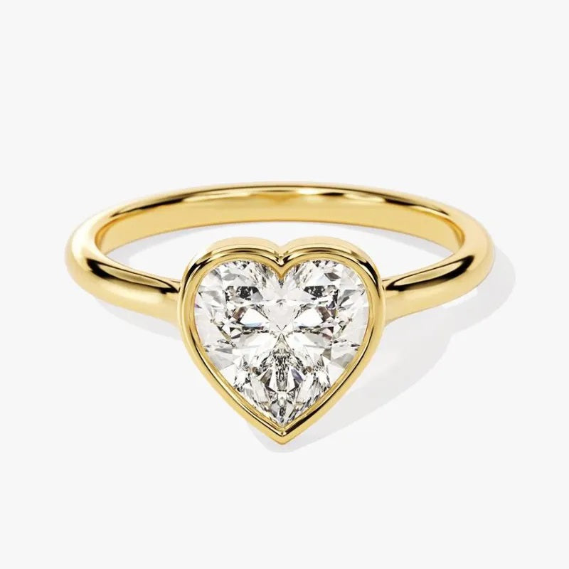  Heart shae Moissanite lab grown diamond engagement ring round shank with a bezel setting, on a gold band, against a white background.Moissanite engagement ring cape town south africa grand diamonds ralph jacobs jeulia 