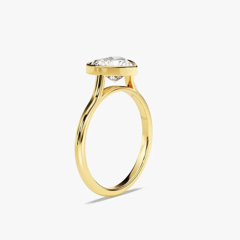  Heart shape Moissanite lab grown diamond engagement ring round shank with a bezel setting, on a gold band, against a white background.Moissanite engagement ring cape town south africa grand diamonds ralph jacobs jeulia 