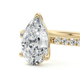 Pear cut Moissanite lab grown diamond engagement ring half eternity set shank with classic three prong setting, on a gold band, against a white background.Moissanite engagement ring cape town south africa grand diamonds ralph jacobs jeulia 