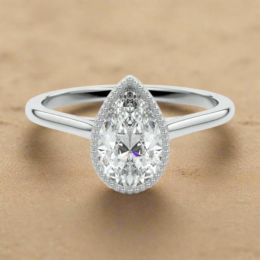 Pear shape Moissanite lab grown diamond engagement ring round shank with a bezel setting, on a gold band, against a white background.Moissanite engagement ring cape town south africa grand diamonds ralph jacobs jeulia 