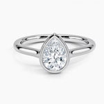 Pear shape Moissanite lab grown diamond engagement ring round shank with a bezel setting, on a gold band, against a white background.Moissanite engagement ring cape town south africa grand diamonds ralph jacobs jeulia 
