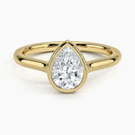 Pear shape Moissanite lab grown diamond engagement ring round shank with a bezel setting, on a gold band, against a white background.Moissanite engagement ring cape town south africa grand diamonds ralph jacobs jeulia 