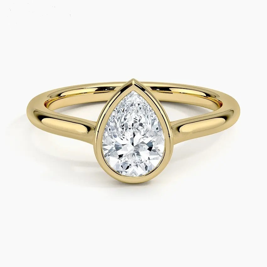 Pear shape Moissanite lab grown diamond engagement ring round shank with a bezel setting, on a gold band, against a white background.Moissanite engagement ring cape town south africa grand diamonds ralph jacobs jeulia 