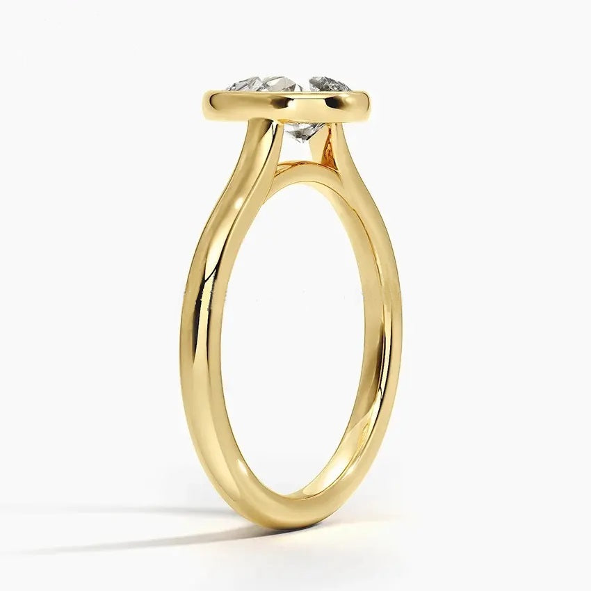 Pear shape Moissanite lab grown diamond engagement ring round shank with a bezel setting, on a gold band, against a white background.Moissanite engagement ring cape town south africa grand diamonds ralph jacobs jeulia 