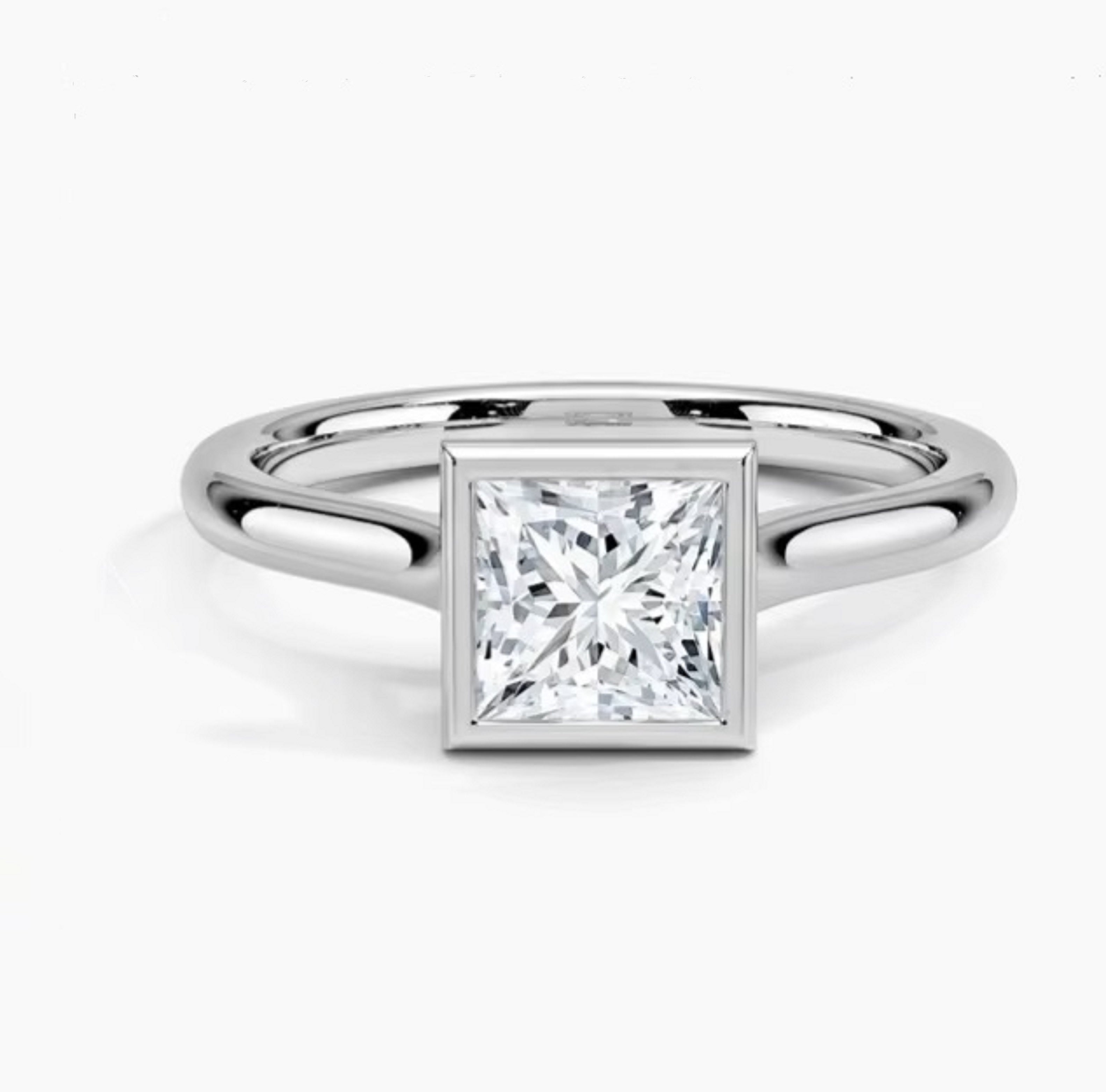 Princess cut Moissanite lab grown diamond engagement ring round shank with a bezel setting, on a gold band, against a white background.Moissanite engagement ring cape town south africa grand diamonds ralph jacobs jeulia 