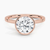 Round cut Moissanite lab grown diamond engagement ring round shank with a bezel setting, on a gold band, against a white background.Moissanite engagement ring cape town south africa grand diamonds ralph jacobs jeulia 
