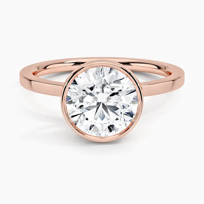 Round cut Moissanite lab grown diamond engagement ring round shank with a bezel setting, on a gold band, against a white background.Moissanite engagement ring cape town south africa grand diamonds ralph jacobs jeulia 