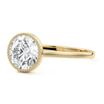 Round cut Moissanite lab grown diamond engagement ring round shank with a bezel setting, on a gold band, against a white background.Moissanite engagement ring cape town south africa grand diamonds ralph jacobs jeulia 