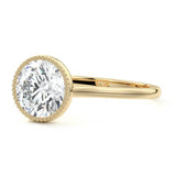 Round cut Moissanite lab grown diamond engagement ring round shank with a bezel setting, on a gold band, against a white background.Moissanite engagement ring cape town south africa grand diamonds ralph jacobs jeulia 