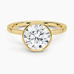 Round cut Moissanite lab grown diamond engagement ring round shank with a bezel setting, on a gold band, against a white background.Moissanite engagement ring cape town south africa grand diamonds ralph jacobs jeulia 