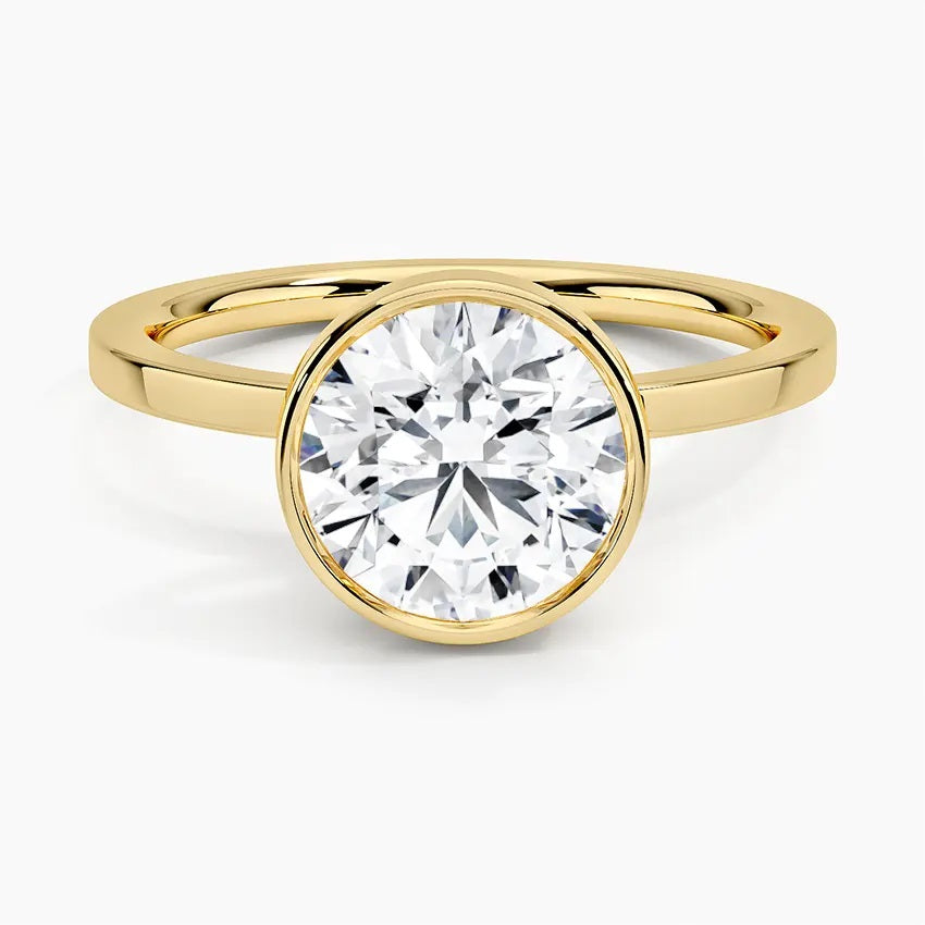 Round cut Moissanite lab grown diamond engagement ring round shank with a bezel setting, on a gold band, against a white background.Moissanite engagement ring cape town south africa grand diamonds ralph jacobs jeulia 