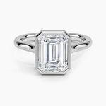 alt="An Emarald cut Moissanite engagement ring round shank with a bezel setting, on a gold band, against a white background.Moissanite engagement ring cape town south africa grand diamonds ralph jacobs jeulia 