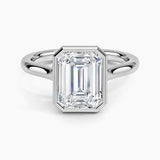 alt="An Emarald cut Moissanite engagement ring round shank with a bezel setting, on a gold band, against a white background.Moissanite engagement ring cape town south africa grand diamonds ralph jacobs jeulia 