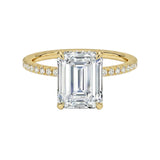 Gold ring with a large emerald-cut diamond and smaller diamonds on a white background