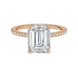 Rose gold ring with a large emerald-cut diamond and smaller diamonds on the band against a white background