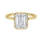 Modern bezel set emerald cut moissanite solitaire ring with a flat gold band ApolloGem